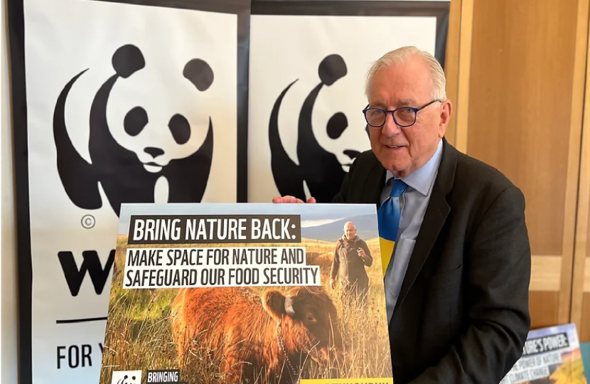 Sir Peter Bottomley in front of a WWF poster